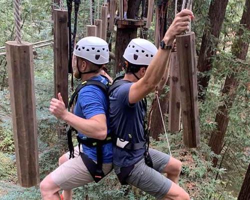 Livermore employees using teamwork to traverse a cable bridge on Mount Hermon